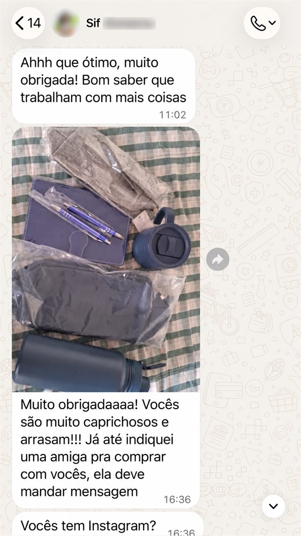 Print de conversa no WhatsApp com uma cliente. Ela escreve “Ahhh que ótimo, muito obrigada! Bom saber que trabalham com mais coisas”, envia a foto do kit recebido — caderneta azul-marinho, duas canetas, copo térmico, necessaire e garrafa térmica, ainda embalados — e completa: “Muito obrigadaaaa! Vocês são muito caprichosos e arrasam!!! Já até indiquei uma amiga pra comprar com vocês, ela deve mandar mensagem”.